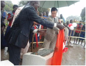 Ambassador unveils the plaque amidst a heavy downpour