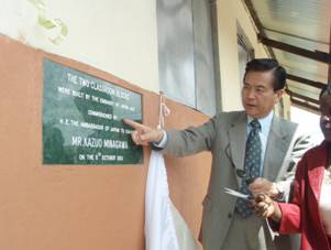 Ambassador reads up the memorial plaque in Rwenyange Primary School