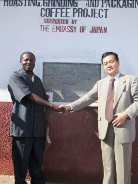 Ambassador and Head of implementing organization shaking hands in front of plaque